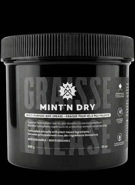 Black container of Mint 'N Dry grease with visible branding on a black background